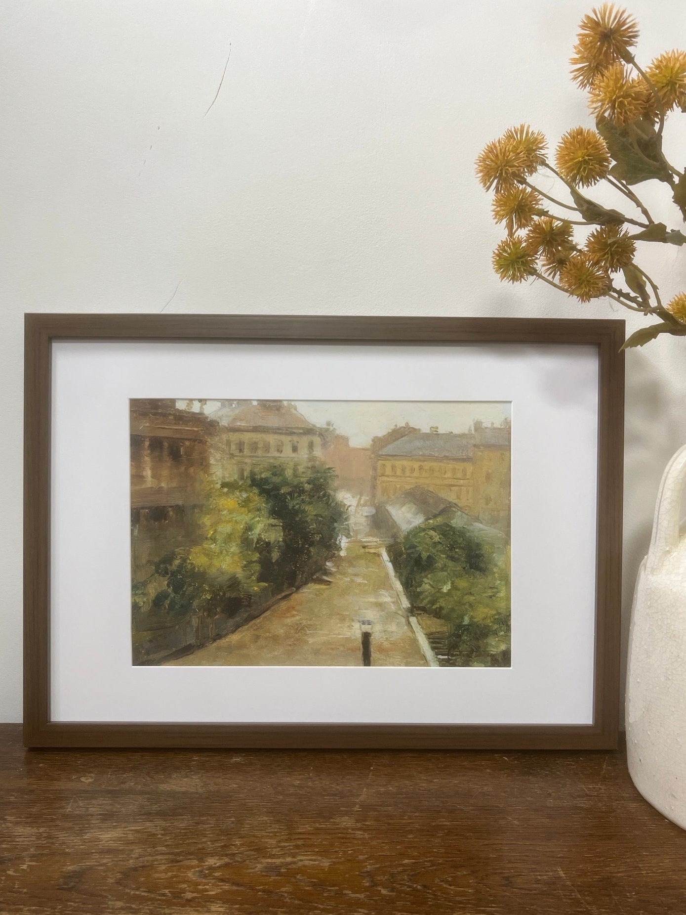 Framed artwork on a wooden surface with a white wall in the background